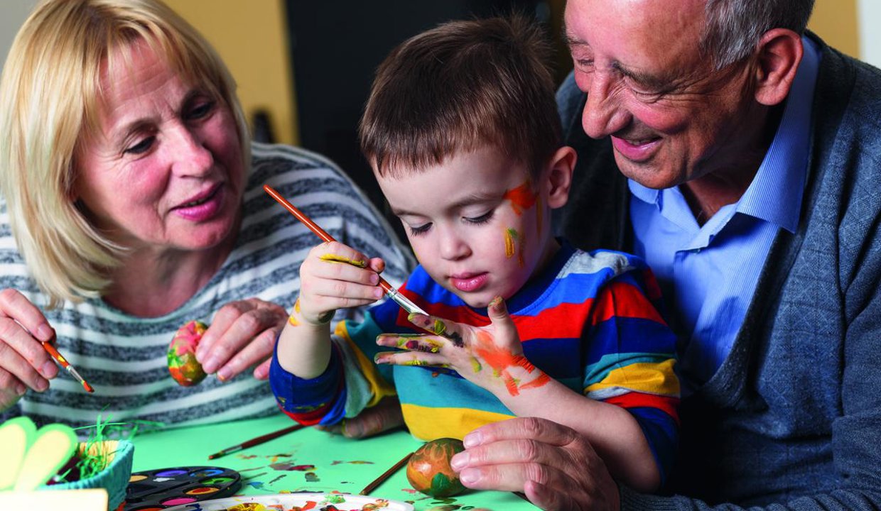 Child painting with two adults